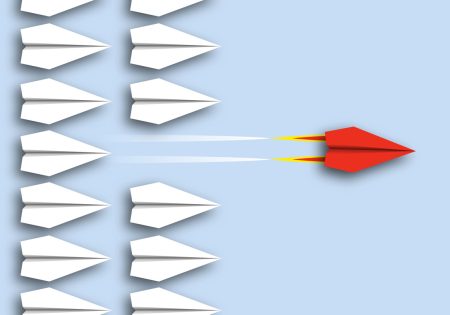 The case for viewing operational resilience as a competitive advantage A red paper aeroplane speeds ahead of a pack of white aeroplanes, showing competitive advantage