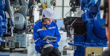 an engineer in uniform and helmet inspects heavy machinery.