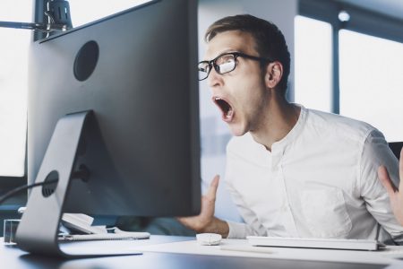 Cyber attacks are the top cause of organizational downtime and recovery is becoming more difficult A worker reacts angrily as downtime impacts his work.