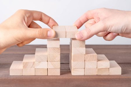 Break down organizational silos by building bridges. Picture shows two sets of blocks being joined together by a bridge made of two additional blocks.