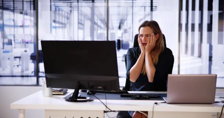 A female executive reacts with stress due to an issue with her computer