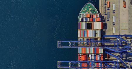 Global Supply Chain Continuity Index dips in wake of disruptions to key shipping routes Aerial top down ultra wide photo of industrial container ship loading - unloading colourful truck size containers with cranes in logistics terminal.