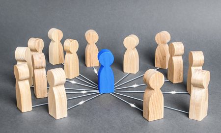 A concept showing that leaders should be at the heart of their people not above them. A blue person is in the centre of a group of other people.