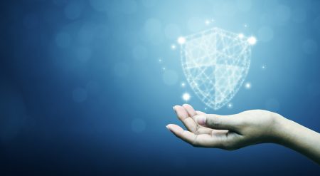 AI and cyber risk: how are insurers addressing the threat and resilience landscape? A business person holds a hand out and holds a futuristic shield.