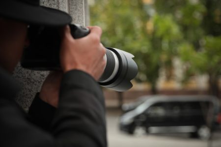 Managing and protecting high-risk individuals in your organization A person with a high-spec camera spies on someone.
