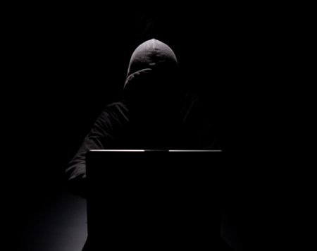 AI is likely to fuel a surge in cyber, fraud, and economic crime warn chief internal auditors Hacker working on laptop in the dark