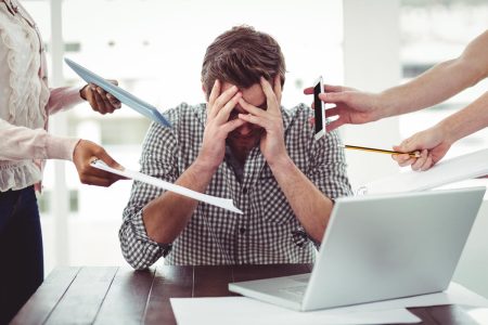 Mental health and wellbeing are a vital aspect of business resilience A stressed employee is pressured from four angles to perform work for other people.