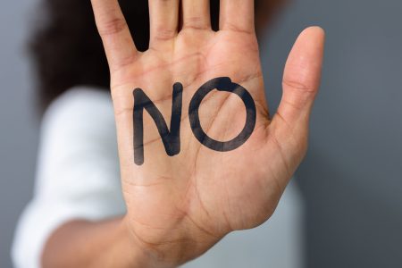 A hand held up with the word No written on the palm.