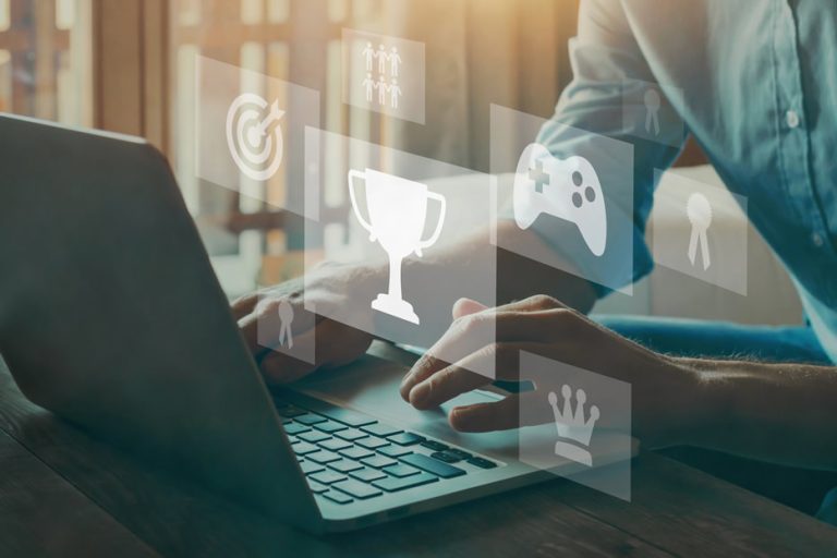 A person active on a laptop with gamification icons coming out of it.