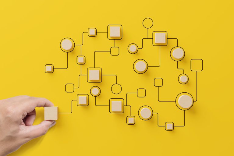whole system - Resilience Forward Hand holding wooden cube block arranging a system on a yellow background