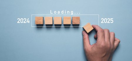 A hand placing a 2025 block into a line of blocks indicating the progress of 2024.