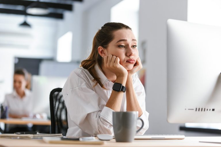 An office worker sits bored in front of her computer due to a virtual desktop infrastructure (VDI) problem.