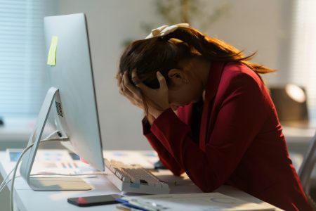 Young businesswoman holding her head in hands.