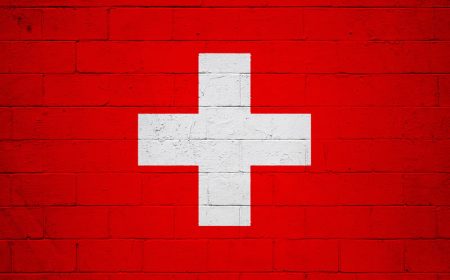 Switzerland is introducing a reporting obligation for cyberattacks on critical infrastructure A Swiss flag overlaid on a brick wall.