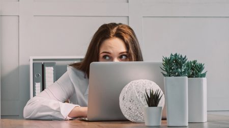 Beyond awareness: engineering resilience against Shadow AI A female worker looks over the top of her laptop to make sure no-one can see what she is doing.
