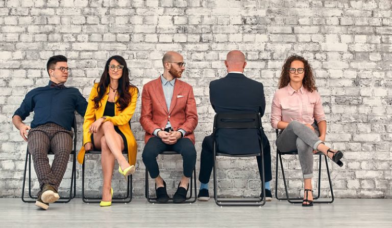 An executive faces a wall as four colleagues look the other way, depicting that the executive is ignoring reality