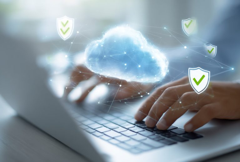 cloud identity management - Resilience Forward Hands typing on laptop with glowing cloud and security shields symbolizing cloud computing and data protection.
