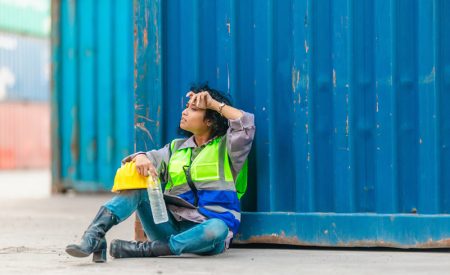 An Exhausted Worker Resting at a Container Yard.
