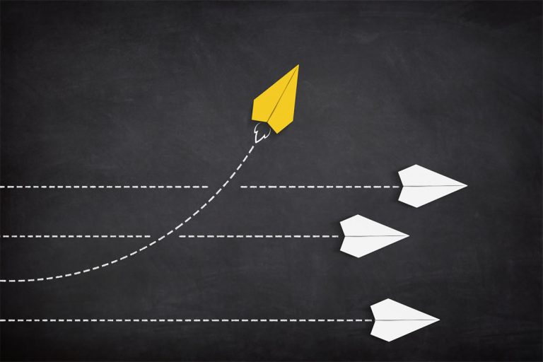 A yellow paper plane coming out from a line of white paper planes.