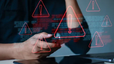 A person using their phone and laptop with a number of red warning triangles popping up.