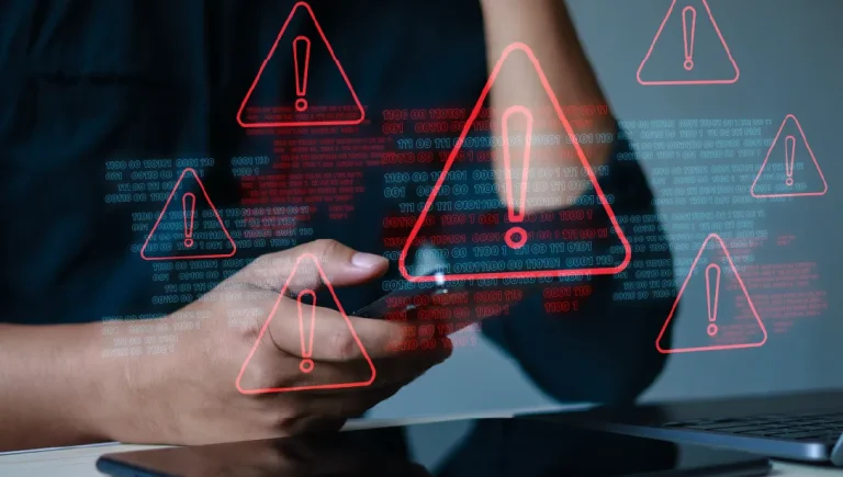 A person using their phone and laptop with a number of red warning triangles popping up.