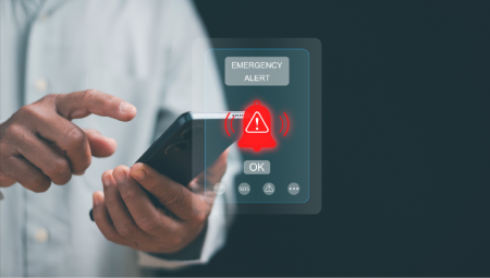 A hand holding a phone which is showing an emergency alert.