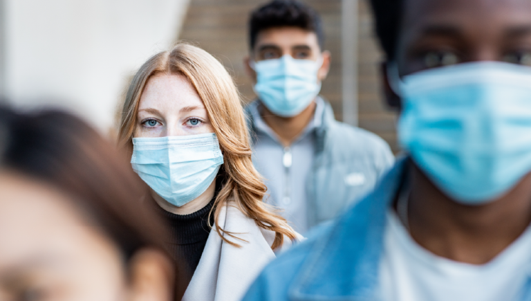 Multiracial people in a city wearing face masks.