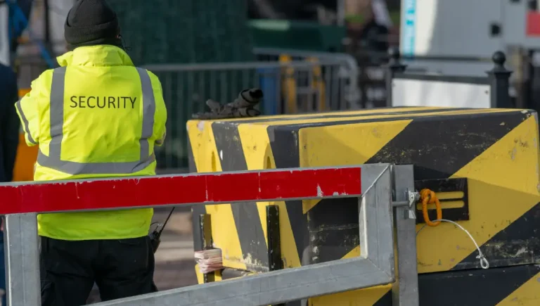 Martyn's law - Resilience Forward A security guard protects an access point with a hostile vehicle management road block to prevent terrorist attacks.