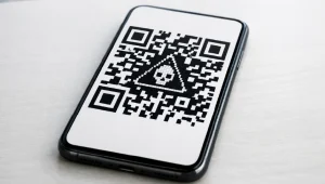 Quishing - Resilience Forward Smartphone on a desk displaying a QR code with a triangle warning containing a skull