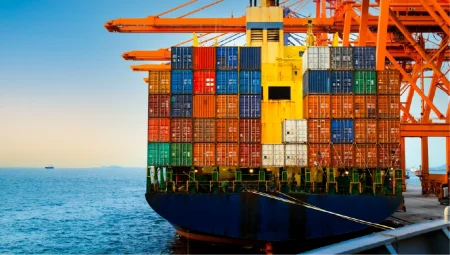 Strengthening supply chain resilience: how business continuity professionals can support procurement teams Rear view of a large container ship being discharged by massive orange quay cranes at a port terminal during sunset.