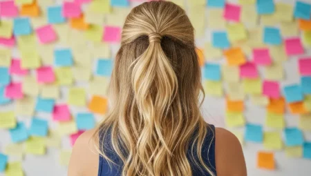 A woman with blonde hair and a ponytail looking at colourful sticky notes on a wall.